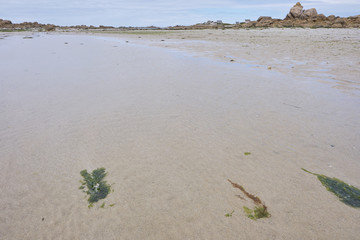 Ebb at a beach at the coastline of Brittany with rocks in the background