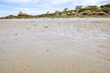 Low tide at a beach in Brittany, coast with rocks, grass and holiday houses
