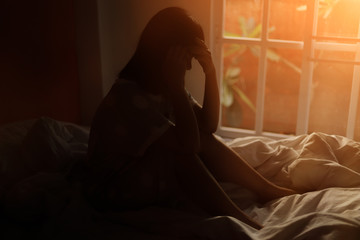 Fototapeta premium The woman sitting on the bed in the bedroom, stress