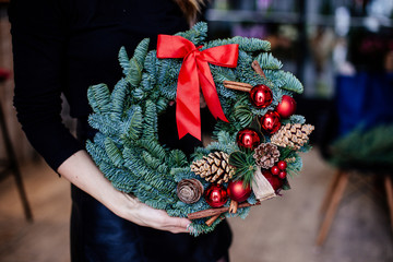 Red christmas wreath in hands.