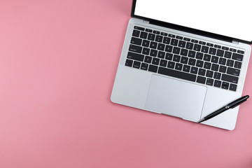 laptop with on pink background. Workspace with jotter and laptop. flat lay, top view