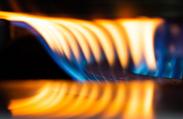 A Macro Image of a Blurry Blue and Yellow Flames on Gas Stove Burner.