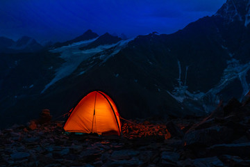 tent in the mountains highlighted inside. the mountains in the background. the dawn of time. Golden hour. a beautiful dawn. Hiking.
