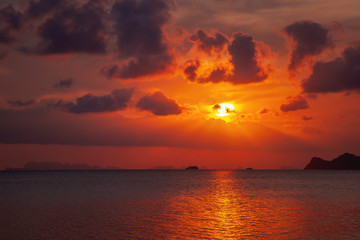 Obraz premium Bright red amazing sunset on the sea, clouds are reflected in the water