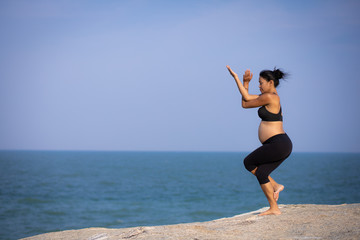 pregnant woman yoga pose on the beach sunset