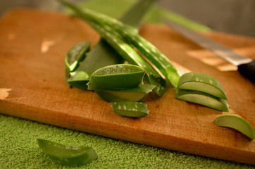 Aloe on a wooden cutting board in the rays of light from the window. Crushed aloe into small pieces...