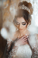 Bridal morning preparation. Beautiful girl with closed makeup eyes.  Newlywed woman final preparation for wedding. Perfect makeup and hairstyle. Bride's preparation at home before the wedding ceremony