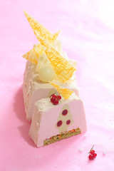 Contemporary Yule Log Cake with pistachio sponge, candied fruits, pistachio mousse, red currant jelly, cream cheese mousse and white chocolate velvet coating, decorated with white chocolate elements, 