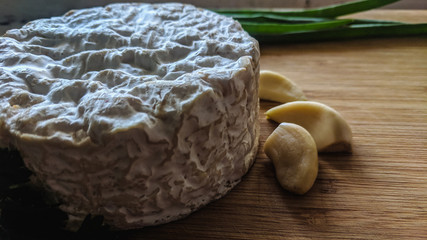 Camembert cheese with garlic and herbs on wooden board