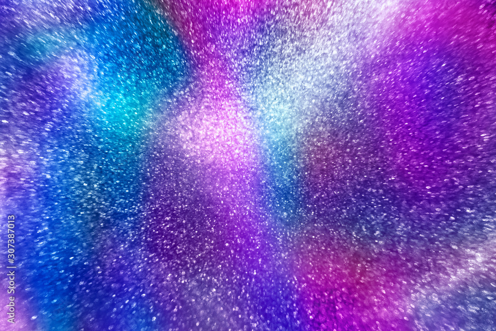 Poster abstract elegant neon rainbow colored glitter particles flow with shallow depth of field underwater.