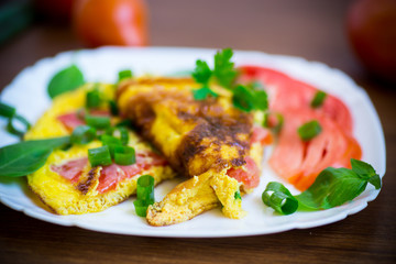 fried omelet from homemade organic eggs with tomatoes and green onions