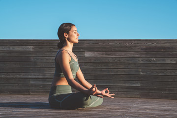 Serene woman meditating in lotus position in sunshine
