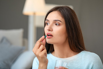 Young woman taking medicine at home
