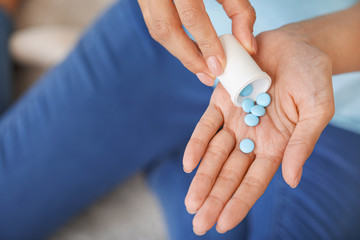 Young woman with pills at home, closeup