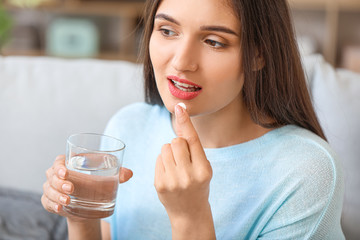 Young woman taking medicine at home