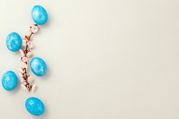 Blue easter eggs with apricot twig on silver textured paper. Top view. Copy space
