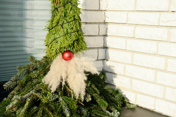 self made christmas imp figure from fir branches sitting in entrance from the house