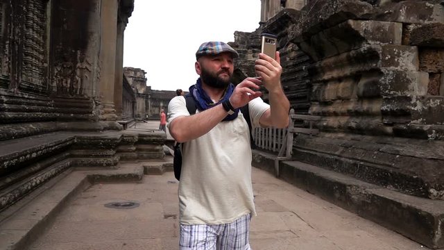 Man taking photos, sightseeing ancient Angkor Wat temple ruins, slow motion
