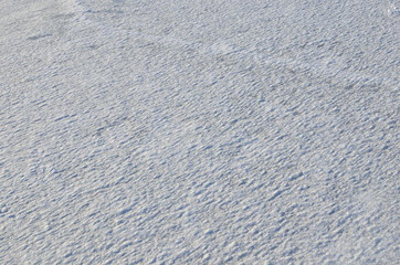 Close up of white snow background. Snow covered ground on a frosty winter day. The concept of colds and blizzards. Frozen river or lake, pure tone texture