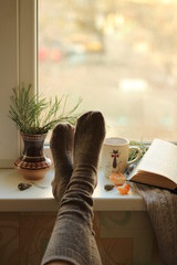 Relaxing with a book and feet in socks on the windowsill
