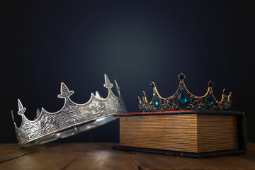 low key image of beautiful queen/king crown over old book and wooden table. vintage filtered. fantasy medieval period © tomertu