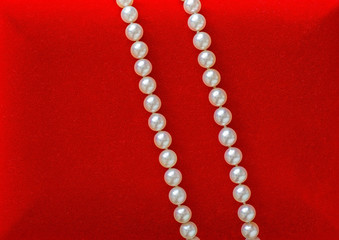 Beautiful natural pearl necklace laid on red velvet jewelry box.