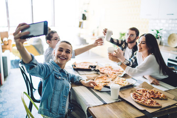 Smiling fellows enjoying food in kitchen and taking selfie