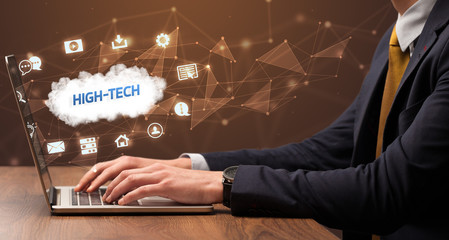Businessman working on laptop with HIGH-TECH inscription, modern technology concept