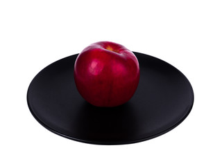 Perfect red apple on black plate isolated on white background. Juicy and fresh apple for ads