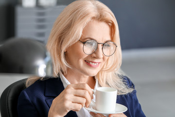 Mature businesswoman drinking coffee in office