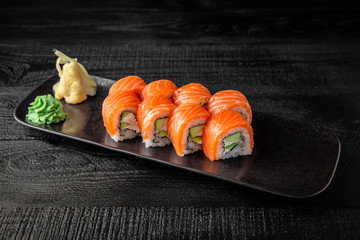 Sushi roll (Philadelphia) with salmon, smoked eel, avocado, cream cheese on black background. Sushi...