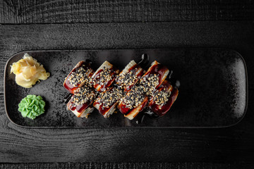 Sushi roll (Maguro) salmon, smoked eel, avocado, philadelphia cheese on black background. Sushi menu. Japanese food.
