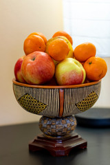 Honey crisp apples and oranges in a pottery bowl sitting on a table.