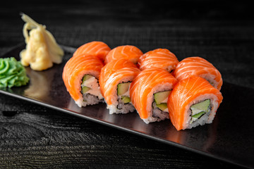 Sushi roll (Philadelphia) with salmon, smoked eel, avocado, cream cheese on black background. Sushi...