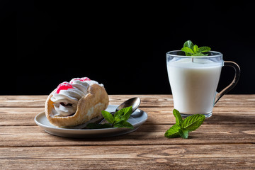Kefir is decorated with a leaf of mint, a fermented drink. Air cake on a saucer. wood background