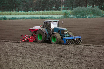Tractor with seed drill and Front Packer which compacts the soil punctiformly into the depth....