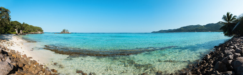 Fototapeta na wymiar A stunning wide panoramic large format photograph of The stunning Anse royal beach in the seychelles, island of mahe. Paradise and beautiful blue sky.
