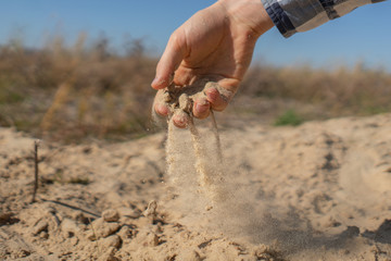 the hand pouring the sand on the beach as the symbol of disappointment and sadness