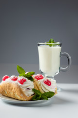 Kefir is decorated with a leaf of mint, a fermented drink. Air cake on a saucer on a white background