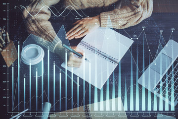 Forex graph on hand taking notes background. Concept of research. Double exposure