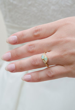 A beautiful expensive aqua iridescent wedding ring with tiny diamonds on a smooth woman hand. Photographed with a shallow depth of field.