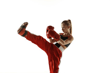 Young female kickboxing fighter training isolated on white background. Caucasian blonde girl in red...