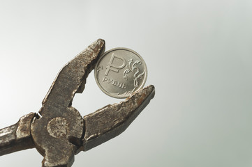 coin denomination of one Russian ruble in old rusty pliers, the concept of the crisis in Russia and...