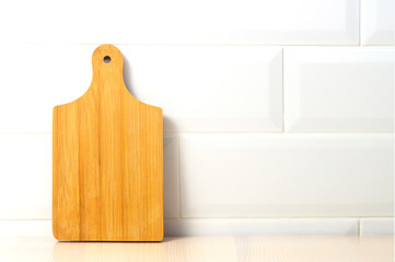 cutting Board on a shelf against a white brick wall