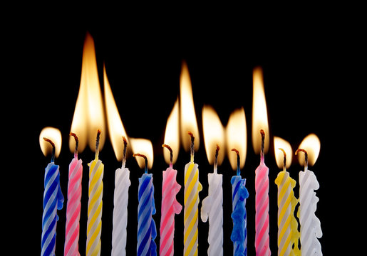 Vivid burning birthday candles on black background