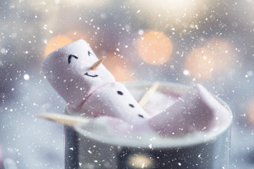 Cute little snowman made from marshmallows bathing in a mug with hot chocolate 