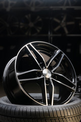 new expensive cast aluminum disc wheel black color, photographed on the tire. dark background,...
