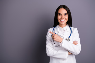 Portrait of her she nice attractive lovely pretty experienced friendly cheerful brunet girl pointing aside copy space 24.7 medical assistance isolated on grey violet purple pastel color background
