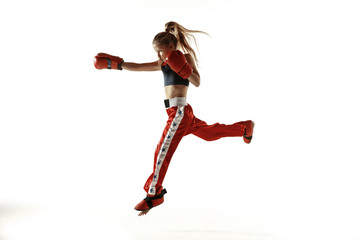 Young female kickboxing fighter training isolated on white background. Caucasian blonde girl in red sportswear practicing in martial arts. Concept of sport, healthy lifestyle, motion, action, youth.