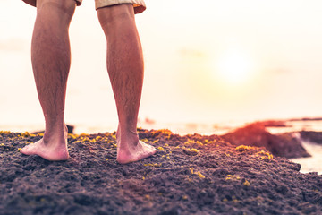 A man standing on the stone  in the beach.